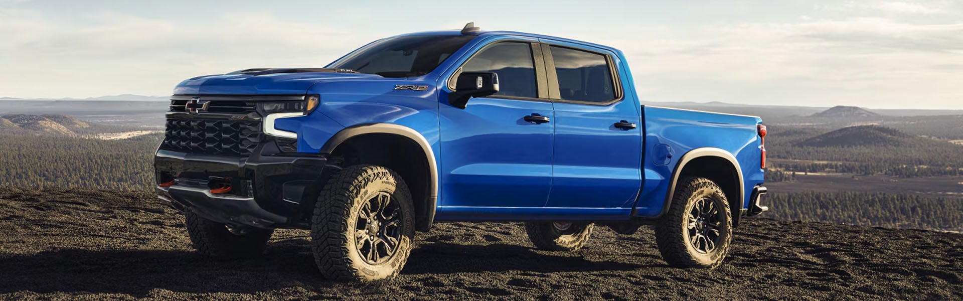 Blue Chevrolet Silverado parked on a rocky desert peak